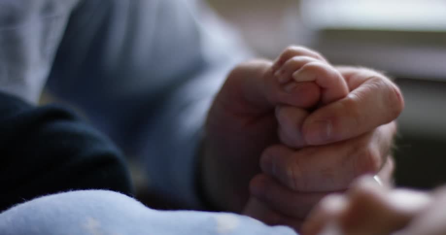 A man holds a baby's hand