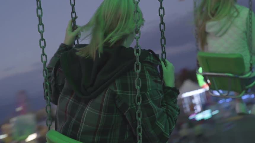 Two women riding on swings at an amusement park