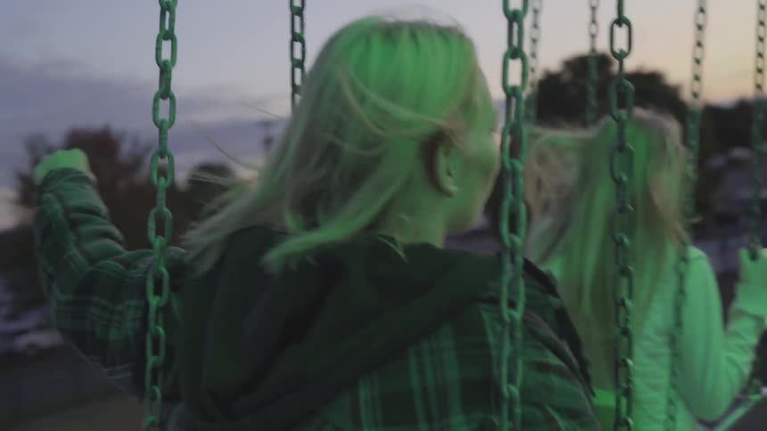 Two girls ride on a fair swing at dusk