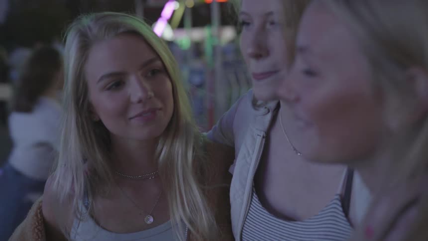 The blonde girls smiling and talking at a fun fair