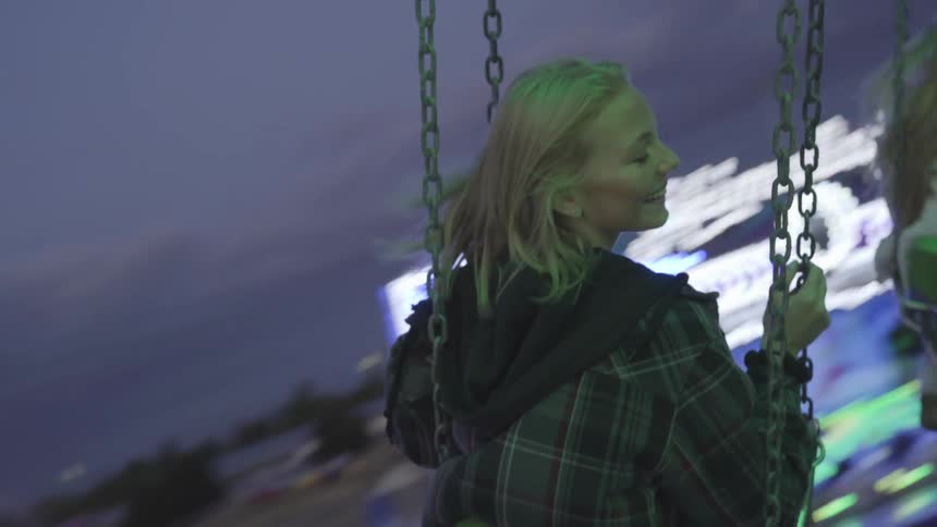 Two teenage girls riding on swings at a carnival