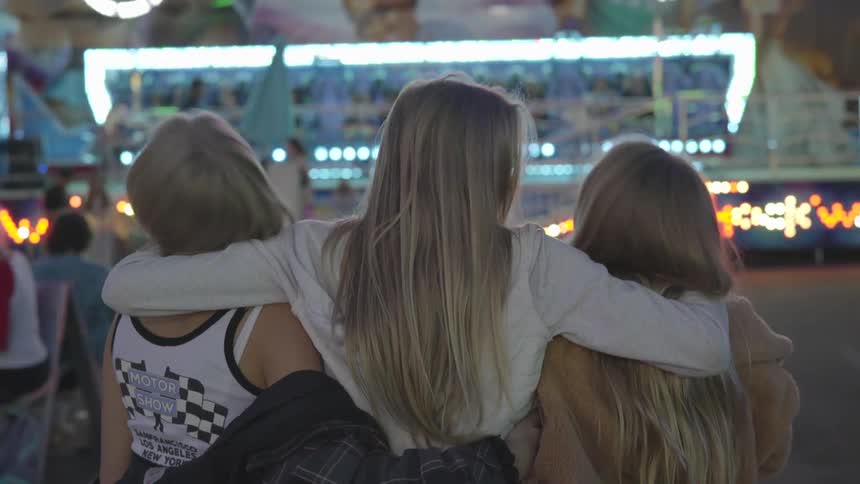 Women are hugging at a carnival at night