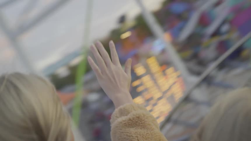 Two blonde teenagers riding a roller coaster at a fair
