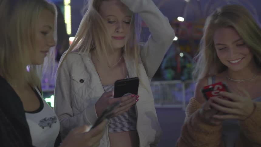 Three girls laughing at their cell phones