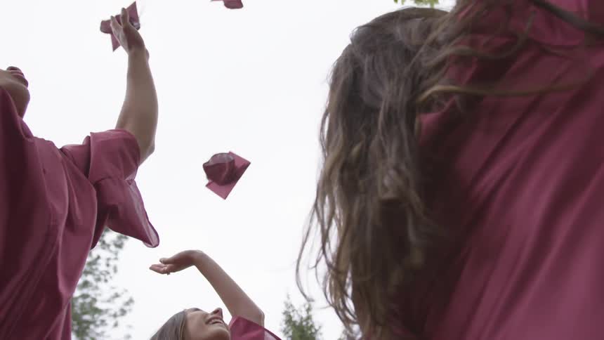 Graduates throw graduation caps in the air