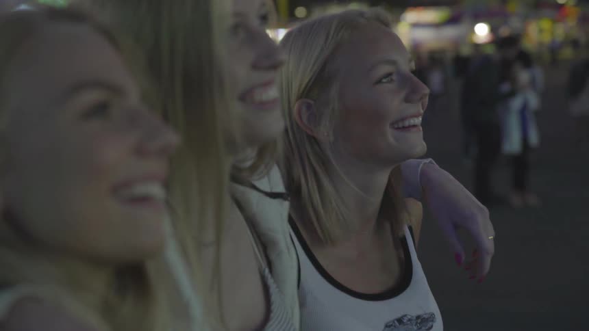 A mom and two teenage girls watching something outside and laughing