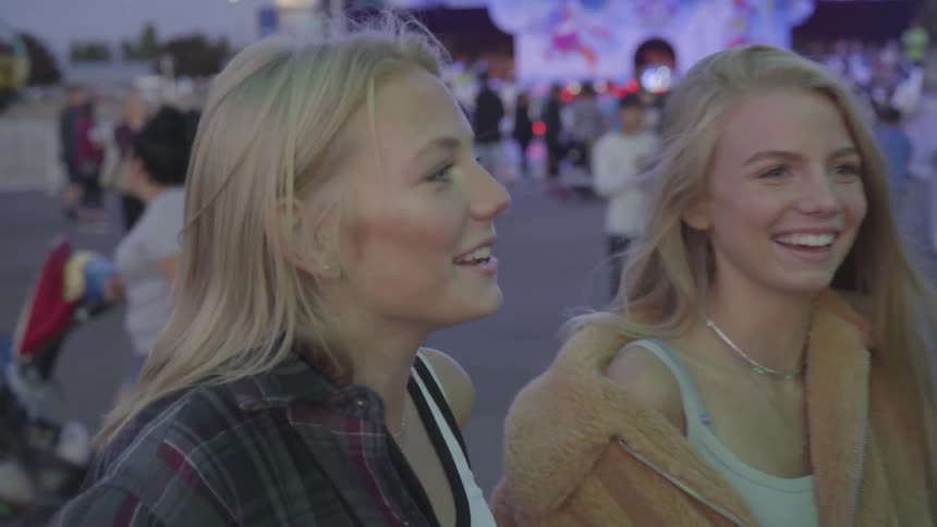 Sisters laughing at a carnival surrounded by other people