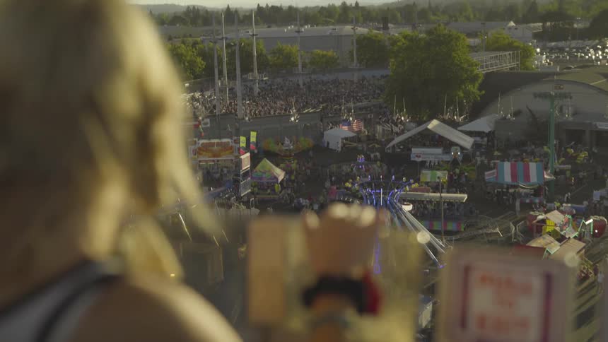 Woman high above carnival points to rides