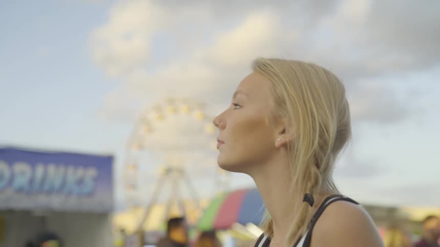 Blonde teenager at a fair looking at the sky