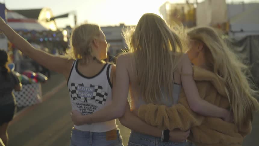 A group of females walking with their arms around each other