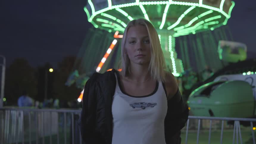 Woman looks into the camera while a ride runs in the background