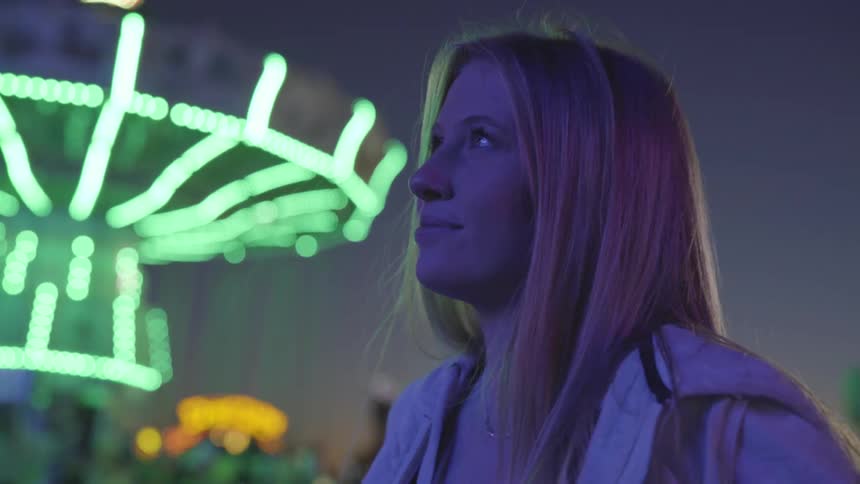 Woman at carnival looks up at lights