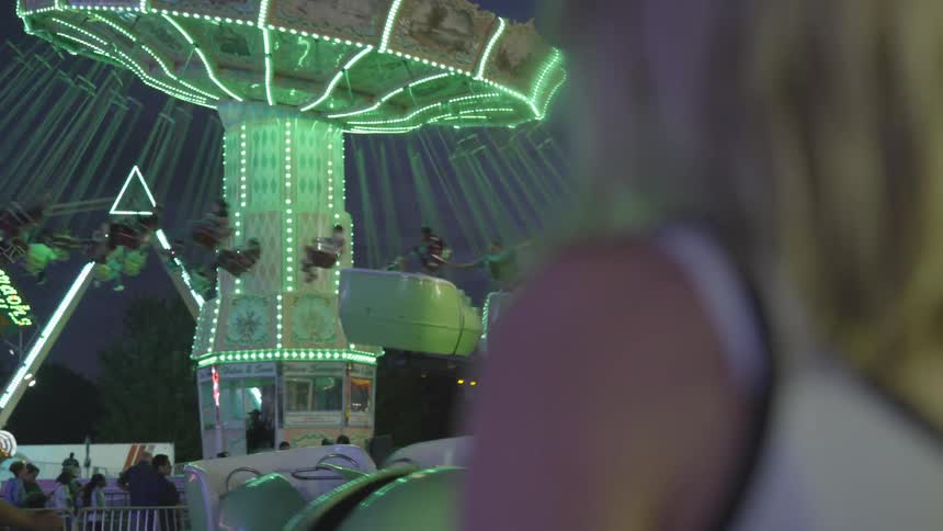 A woman watches a fair swing twirl