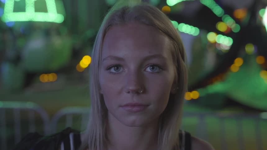 A woman looks into the camera with rides in the background