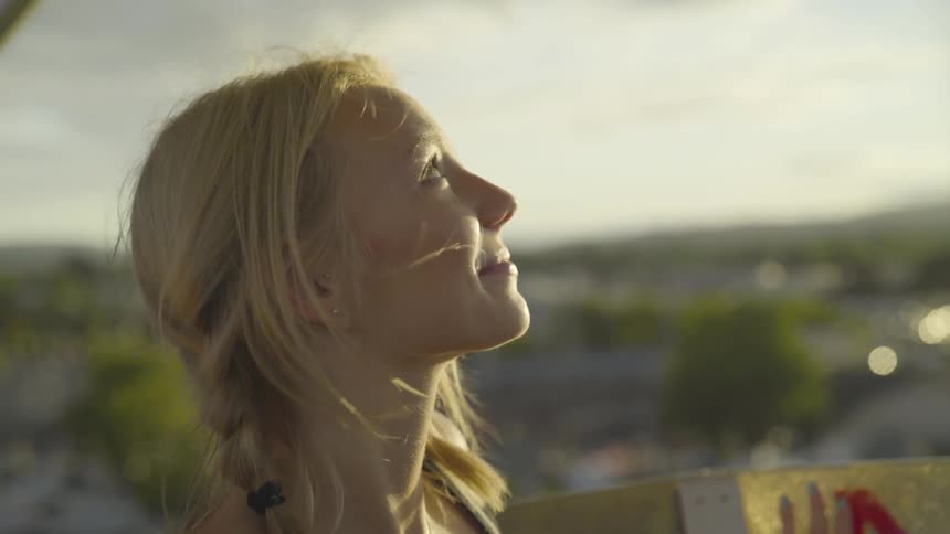 A young woman on a carnival ride outside looking up at the sky