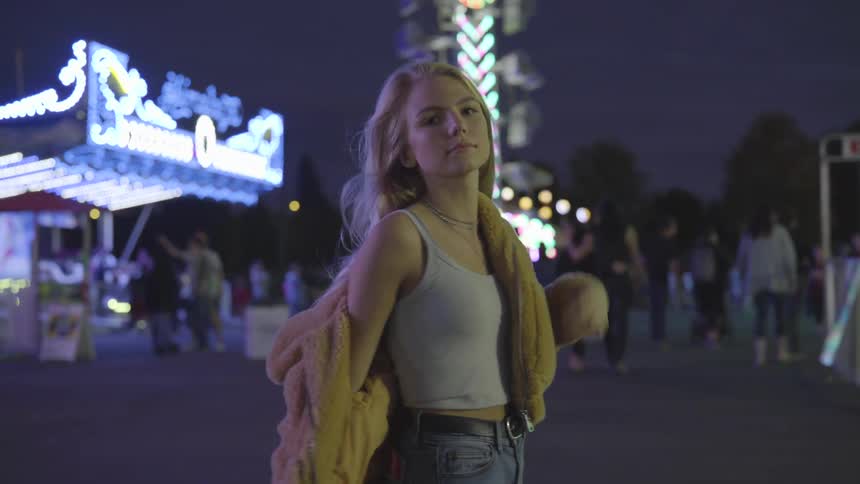 A teenage girl at a fair wearing a yellow jacket