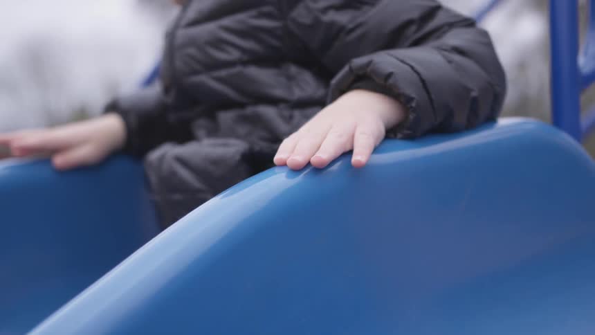 A child sits in a blue seat tapping his fingers