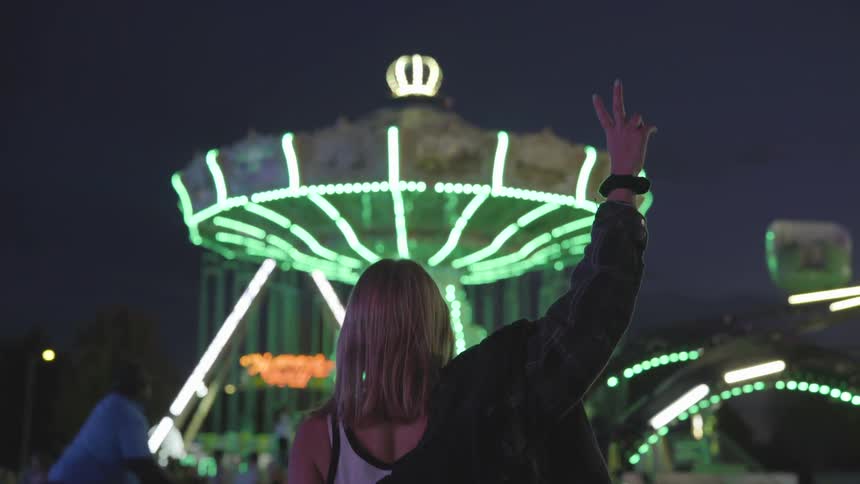 Woman at a fair holding up the peace sign with her fingers