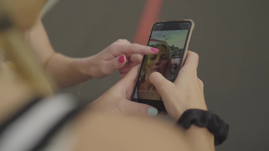 Girl looks at photos on a phone with a friend