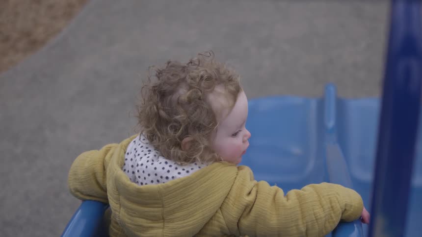 Girl sits at top of blue slide