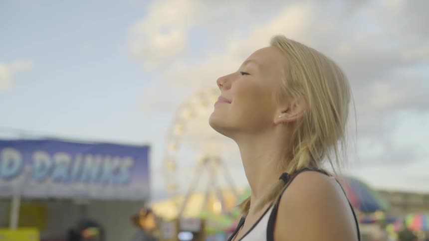 A woman looks up towards the sky while her hair blows in the breeze