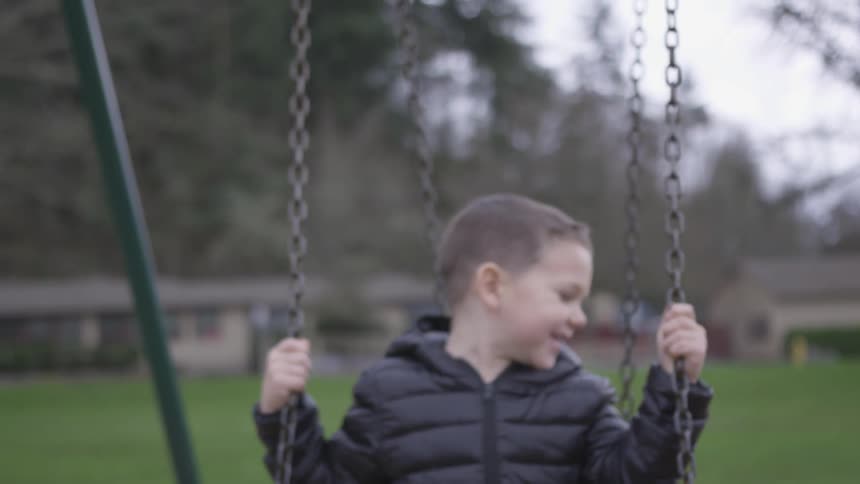 A boy rides a swing in the playground