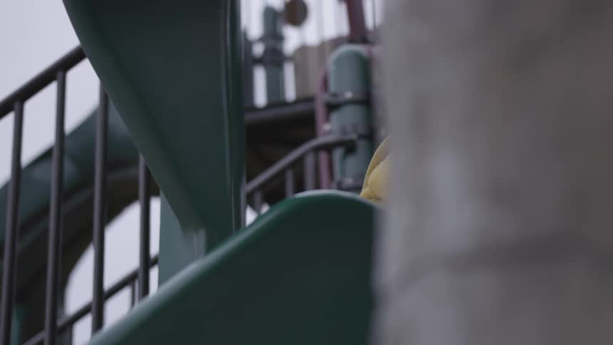 A blonde blue eyed female toddler going backwards down a slide during the day