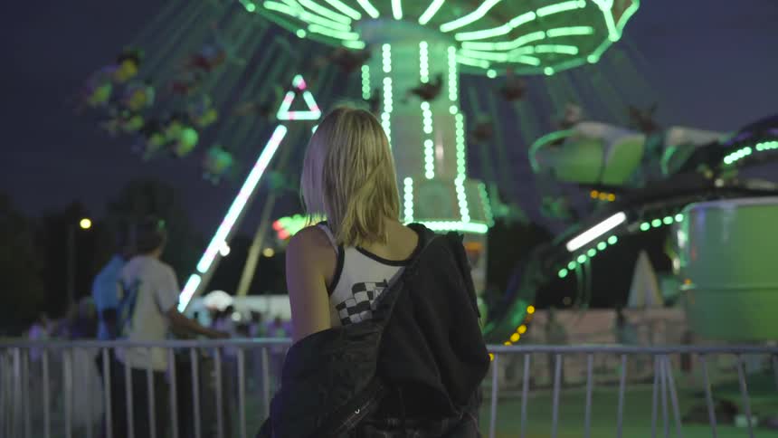Back of girl watching others on amusement park rides