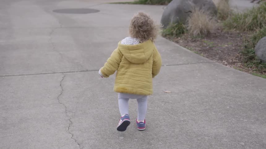 A toddler running own the sidewalk