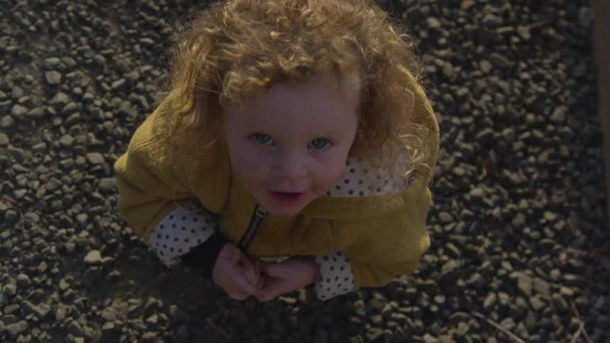 A young girl in a yellow jacket staring up at the sky