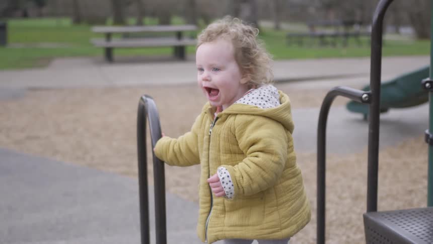 Young girl in coat playing at a park in the fall on a climbing toy