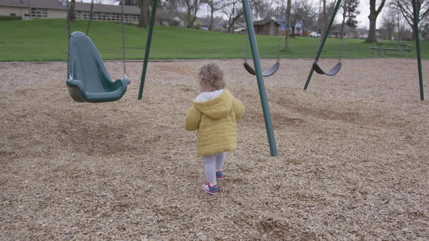 Small girl walks towards swing set