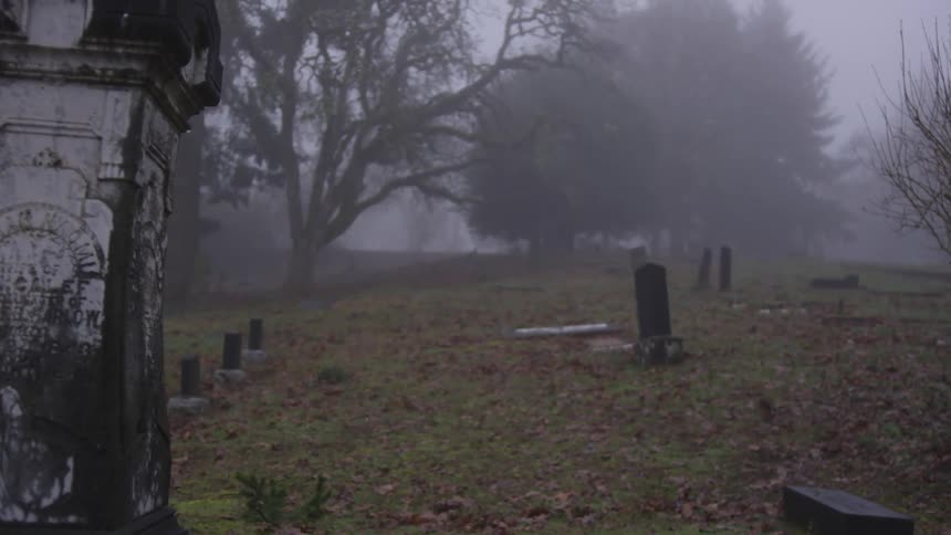 Tilted headstones in a neglected cemetery on a foggy day