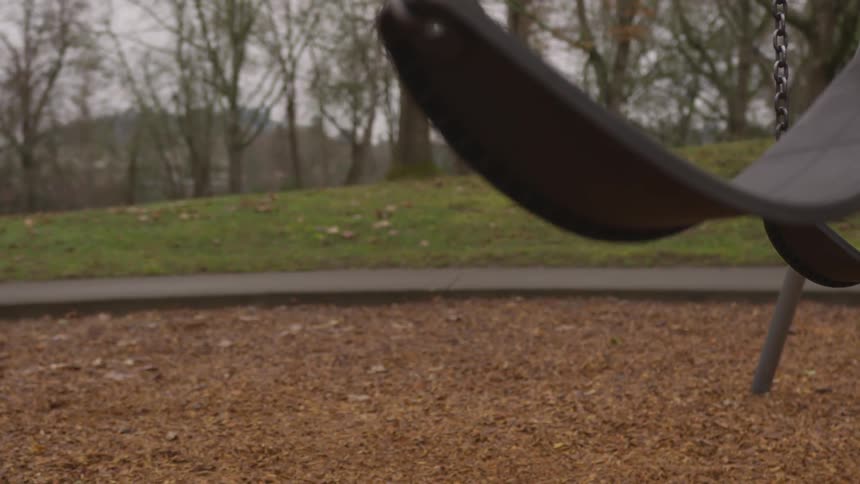 A swing swinging on a swing set at a playground