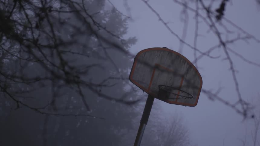 Dirty basketball hoop with clouds in the sky at dusk