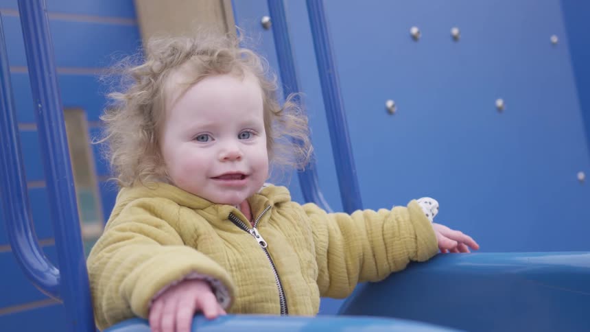 Young girl plays on blue playground equipment