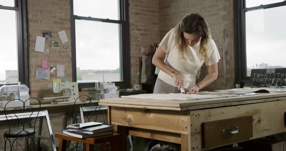 A woman is working on a project at her desk inside