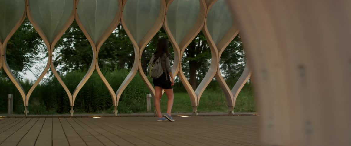 Young woman stands and observes a decorative wall