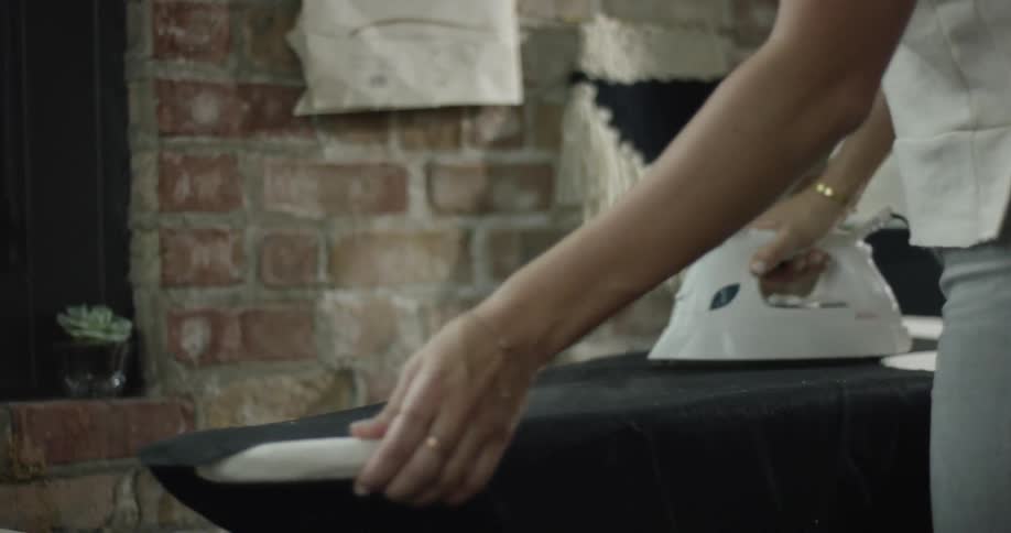 A woman is ironing her dress