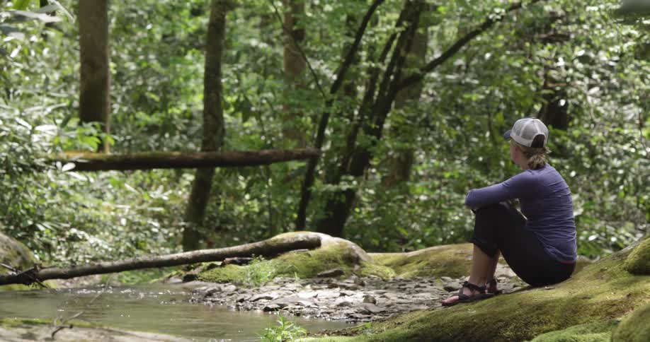 A woman sits in the woods