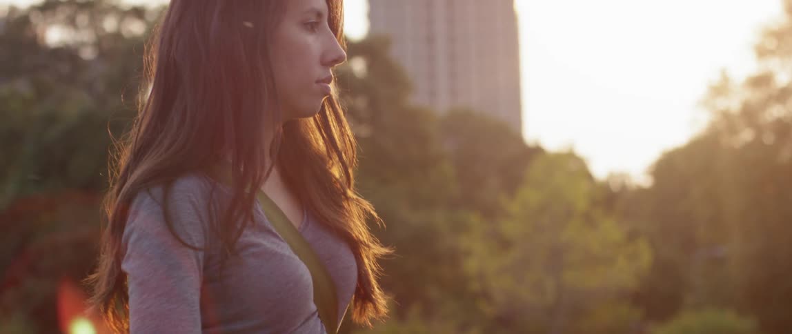 A young woman stares outwards at sunset