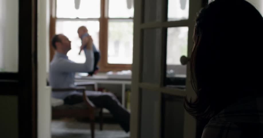 Sitting man raising his infant in an apartment