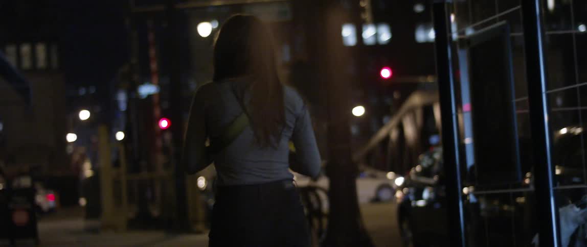 A woman walking down the sidewalk at night