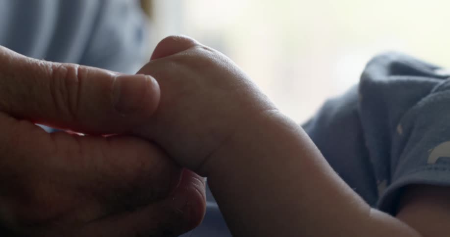 A person holding a baby and touching their hand