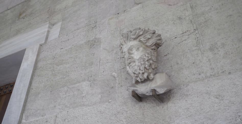 A stone bust of a head is on the wall of a building