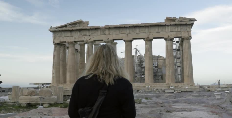 A woman walks towards old ruins