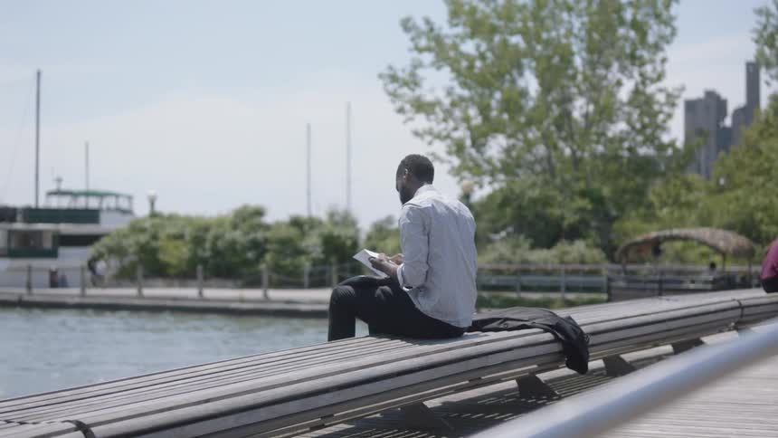 A man is sitting on a bench by the coast
