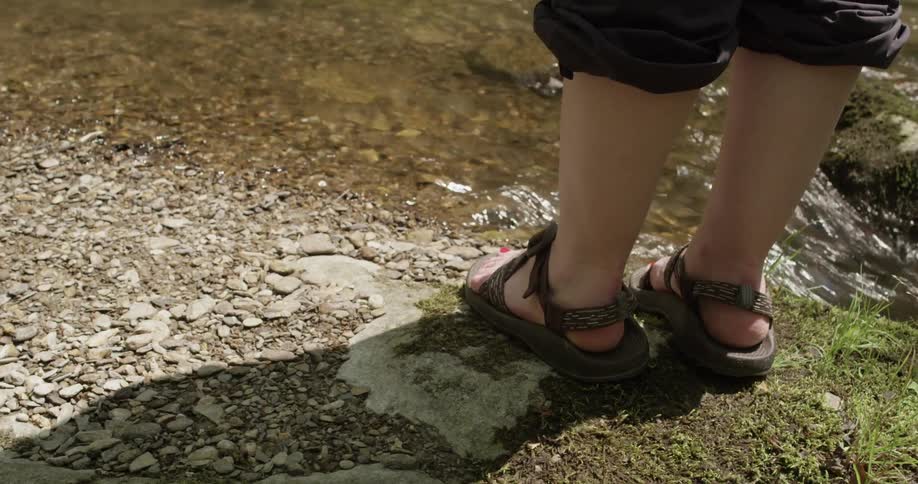 A person standing next to a brook