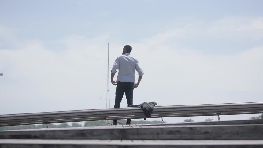 Man places suit jacket on rail and sits down