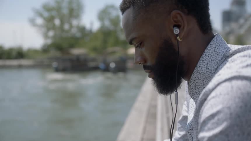 Black man sitting on bench relaxing by a lake
